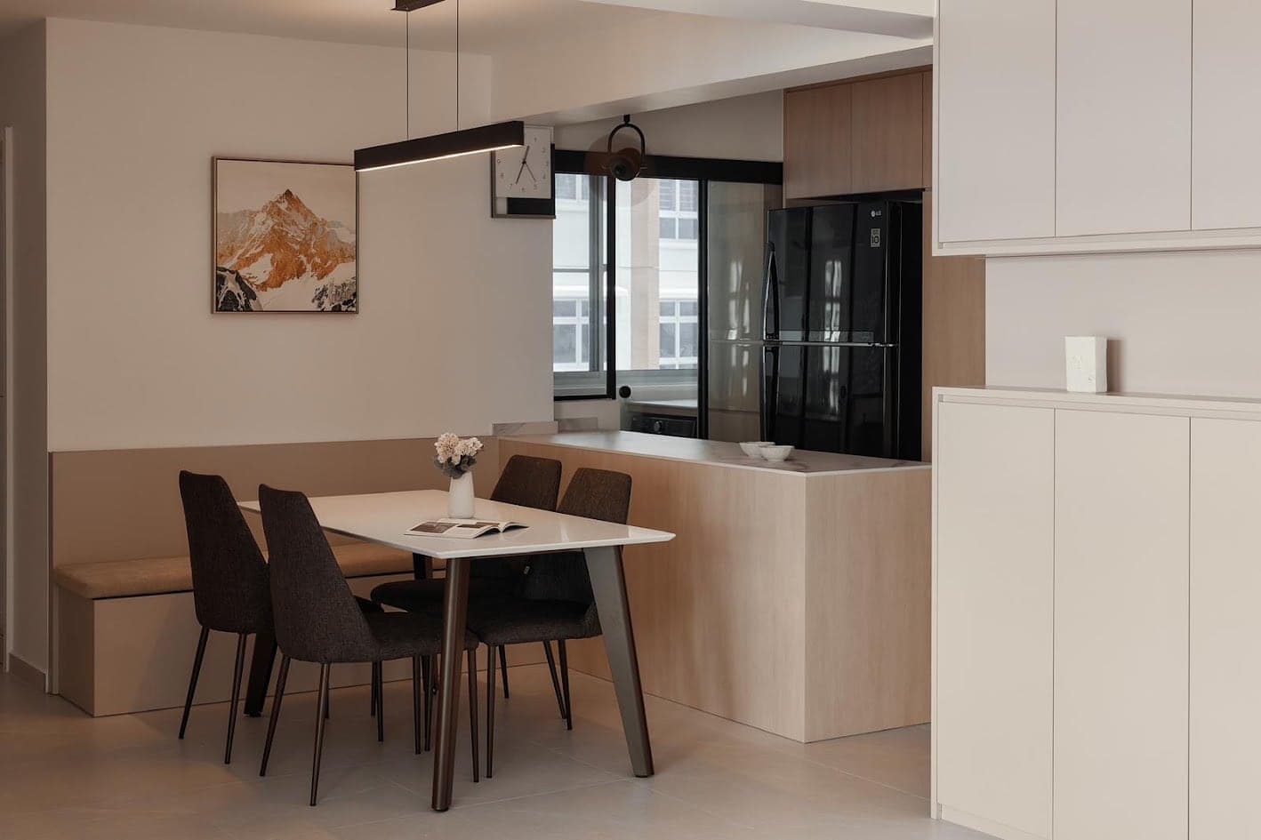 Dining area with a linear pendant over the table and warm concealed light along the bench wall